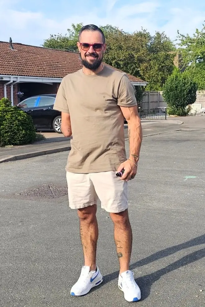Nemo today, 9 stone lighter, standing in a street in a khaki T-shirt, shorts and white trainers