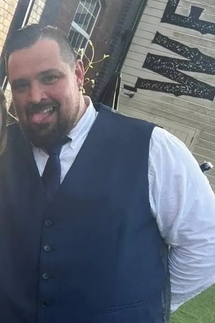 Nemo in 2023, at 22 stone, smiling in a navy waistcoat, white shirt and tie